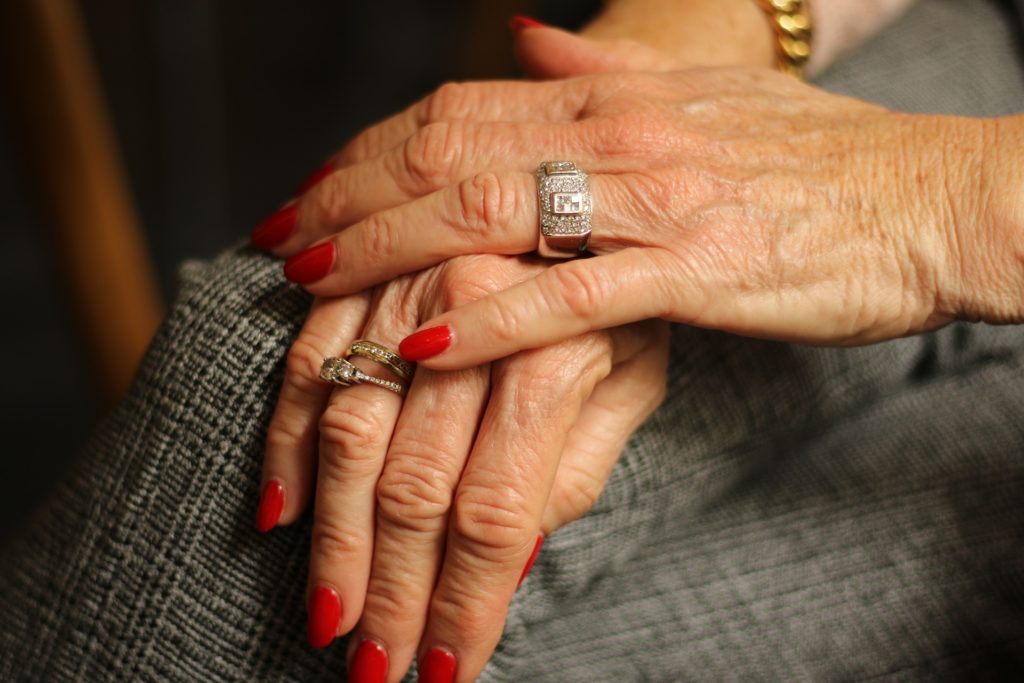 Gros plan sur les mains d'une femme mature avec une manucure rouge, illustrant le soin de la peau et la prévention des taches de vieillesse.