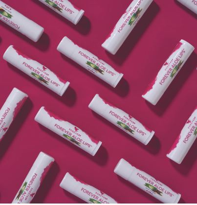 Plusieurs sticks de baume à lèvres Forever Aloe Lips disposés en motif diagonal répétitif sur un fond rose framboise intense.