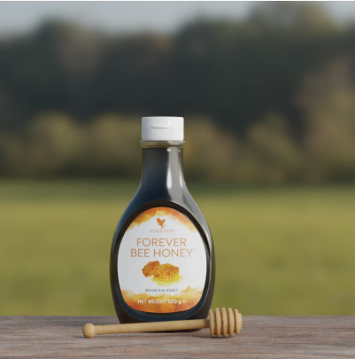 Bouteille de Forever Bee Honey posée sur une table en bois avec une cuillère à miel devant un paysage de campagne verdoyant.