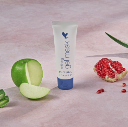 Tube de masque gel de nuit forever posé sur un fond rose avec une pomme verte et une grenade