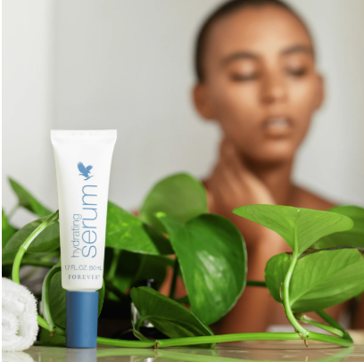 Tube de Forever Hydrating Serum posé au milieu de feuilles vertes luxuriantes, avec une femme à la peau éclatante en arrière-plan flou.