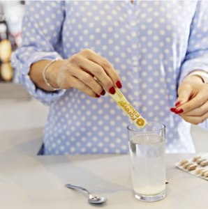 Femme versant un sachet de Forever Fiber dans un verre d'eau pour améliorer son confort digestif et son apport en fibres.